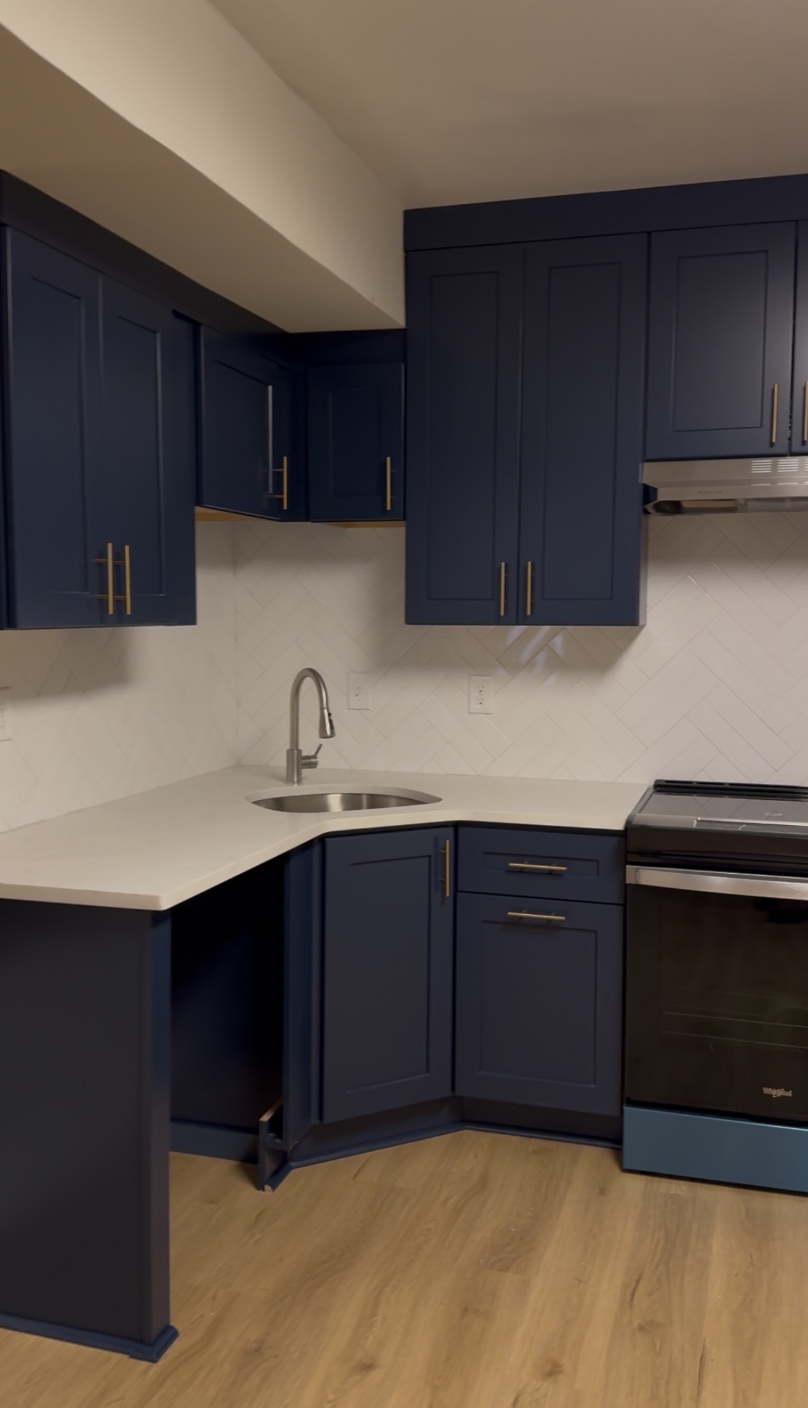 Kitchen with navy shaker cabinets and herringbone backsplash